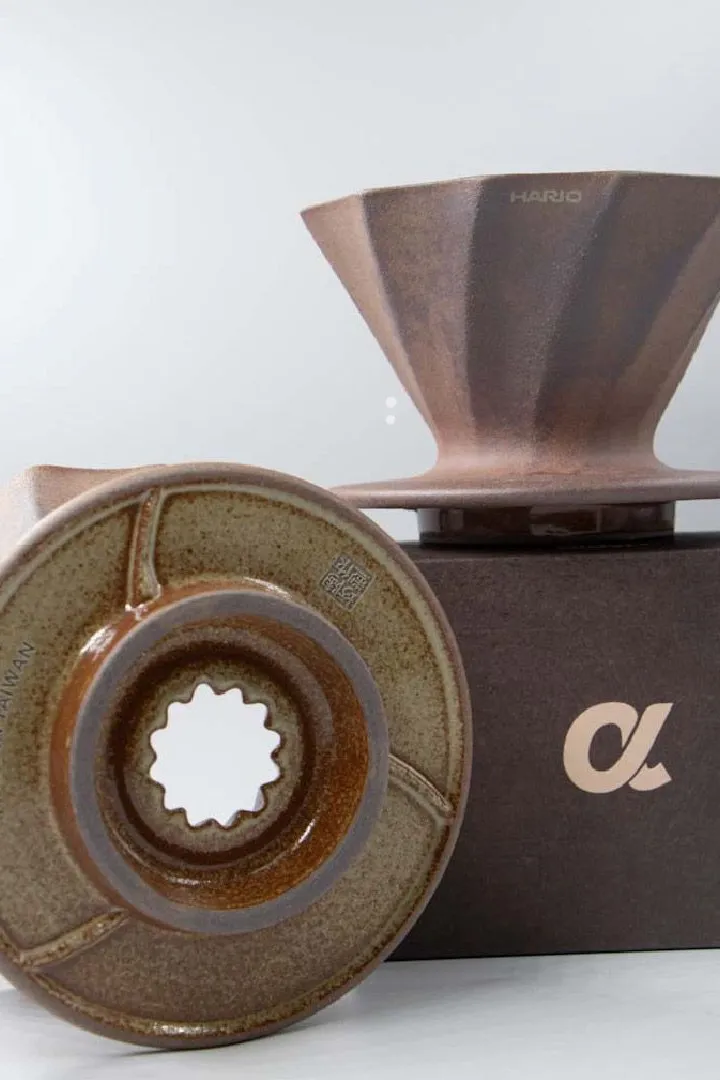 Two Alpha Lao Yan Ni drippers, one standing on its box and one on its side showing the glazed base and single outlet