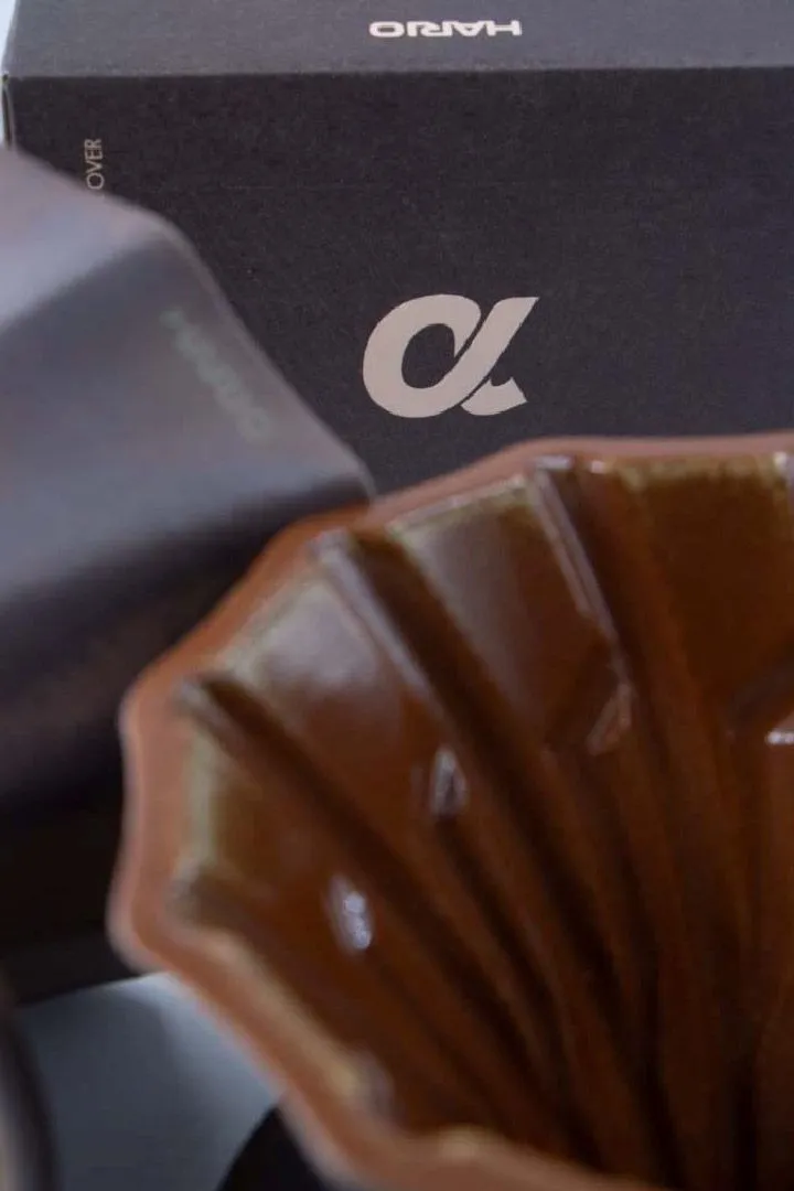 Close-up of the Alpha dripper's ribbed rim in front of a box with the alpha logo